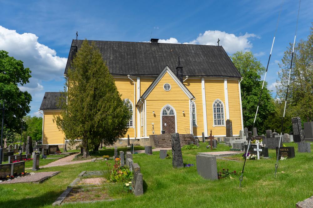 Pusulan kirkko ulkoapäin kuvattuna ja hautausmaata.
