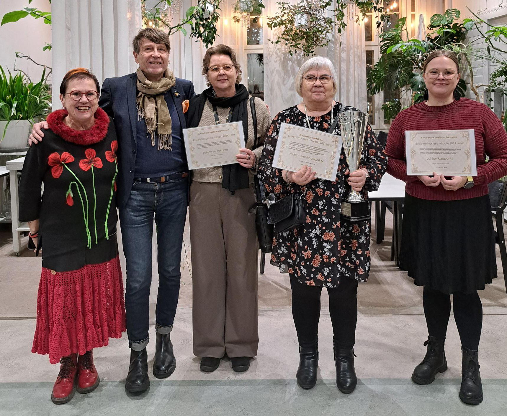 Kuva tilaisuudesta, viisi ihmistä rivissä, kolmella kädessään kunniakirja, yhdellä pokaali