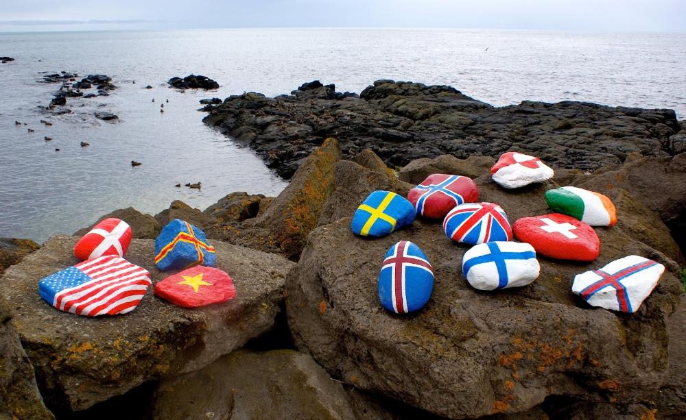 Eri maiden lippuja kalliolle aseteltuna.