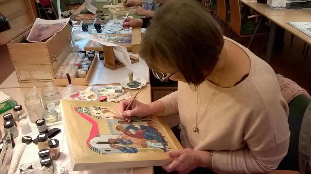 Nainen ikonimaalauskurssilla maalaamassa ikonia.