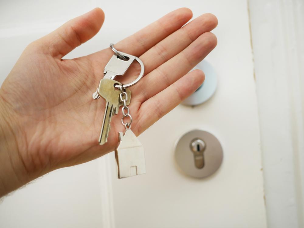 Kaksi avainta ja talo-avaimenperä naisen kädessä.